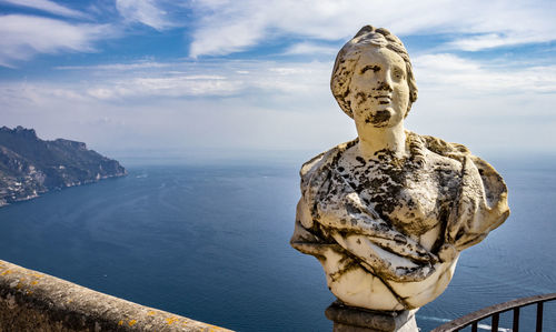 Statue by sea against sky