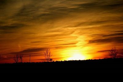 Silhouette landscape against dramatic sky during sunset