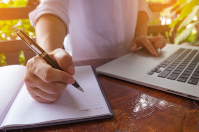 Midsection of man using mobile phone on table