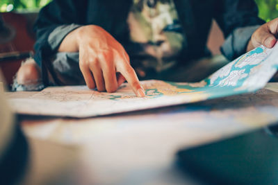 Midsection of man looking at map on table