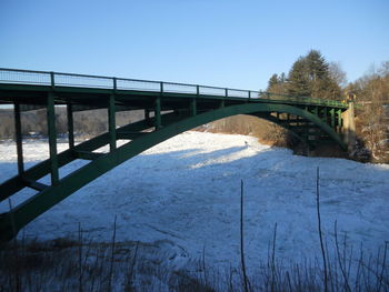 Bridge over river against clear sky during winter