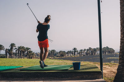 Full length of woman on driving range against clear sky