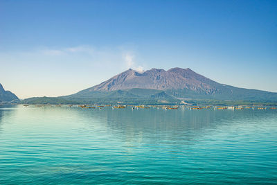 Scenic view of sea and mountains against blue sky