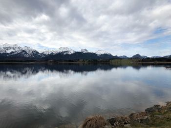 Scenic view of lake by snowcapped mountains against sky