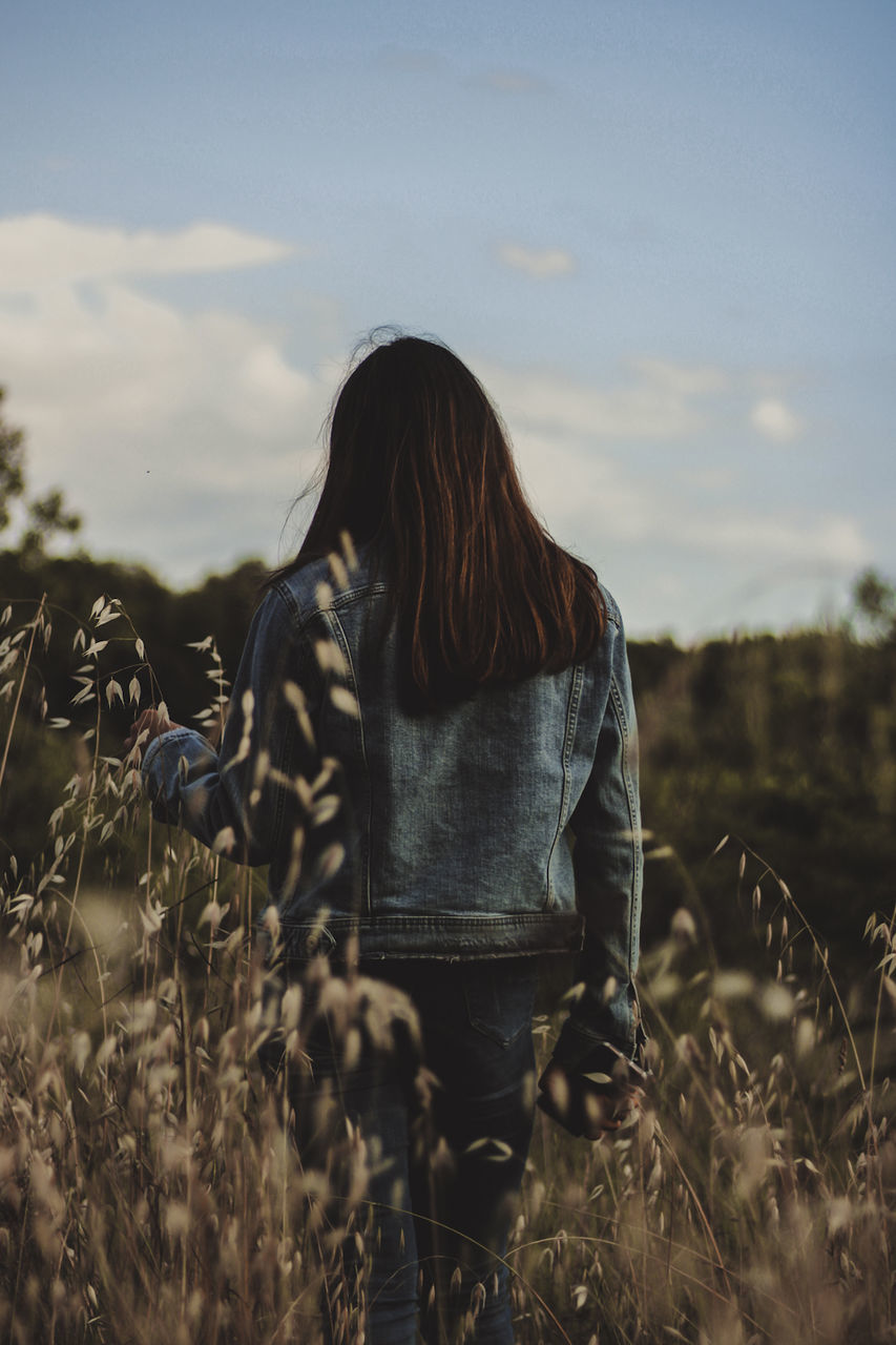 one person, sky, long hair, nature, adult, women, land, hairstyle, rear view, plant, grass, field, sunlight, casual clothing, leisure activity, landscape, young adult, lifestyles, three quarter length, standing, morning, brown hair, environment, autumn, cloud, outdoors, rural scene, day, tranquility, beauty in nature, non-urban scene, rural area, clothing, solitude, person, flower