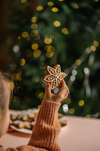 Ginger christmas cookies in children's hands on the background of the christmas tree.