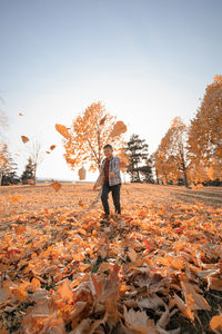 Full length of person standing by tree during autumn against sky