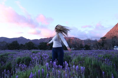 Woman with flowers on field against sky