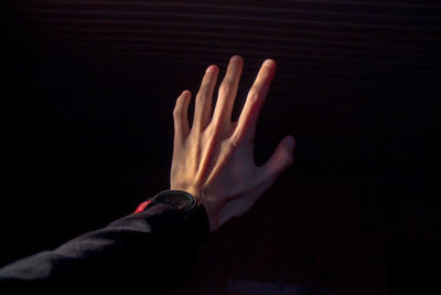 Cropped hand of woman reaching black background