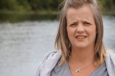 Close-up portrait of woman against lake