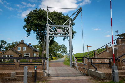 Footpath amidst trees and buildings against sky