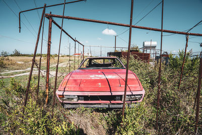 Abandoned car on field against clear sky