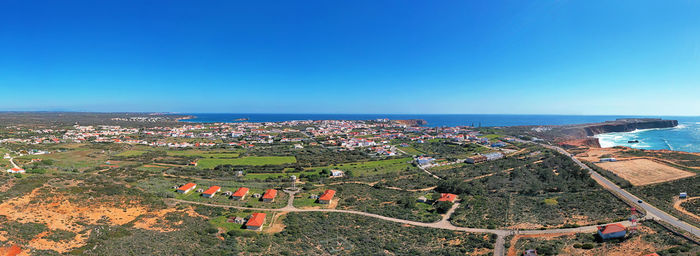 High angle view of sea and buildings against clear blue sky
