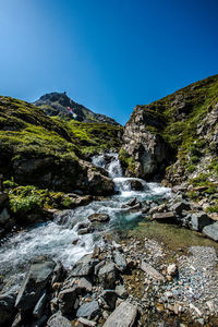 Scenic view of waterfall against clear blue sky