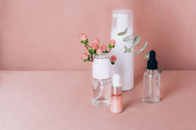 Glass bottles on a shiny pink fabric. serum or essential aroma oil, aromatherapy and massage. 