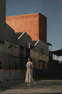 Woman standing by building against sky