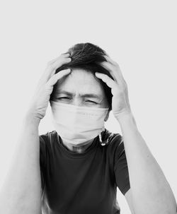 Portrait of boy covering face against white background