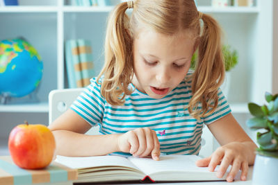 Cute girl with book on table