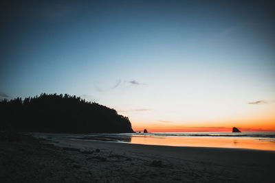 Scenic view of beach against sky at sunset