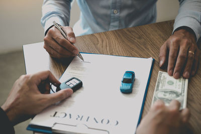 Midsection of man holding paper with text on table