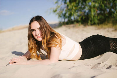 Portrait of young woman lying on sand