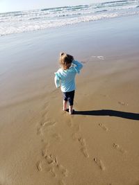 Full length rear view of boy on beach