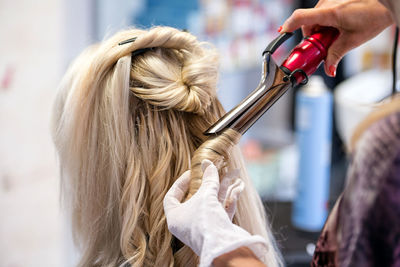 Rear view of hairdresser curling hair