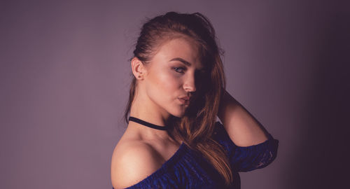 Portrait of beautiful young woman standing against wall