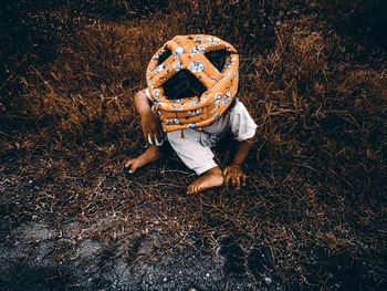 High angle view of baby girl wearing hat sitting on grassy land