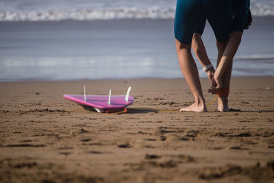 Low section of man wearing belt on leg at beach