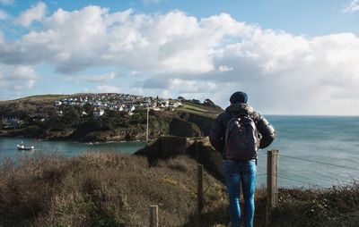 Rear view of man standing by sea against sky