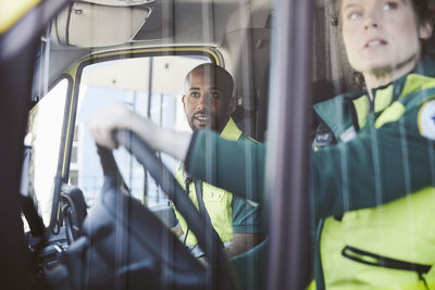 Male and female paramedics looking from ambulance window