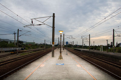 Empty railroad station platform against cloudy sky during sunset