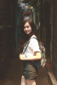 Side view portrait of young woman standing in alley