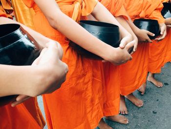 Midsection of monks holding container while standing in shrine