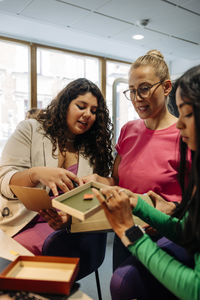 Female entrepreneur discussing with colleagues holding box at office