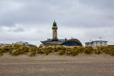 Lighthouse by sea against sky