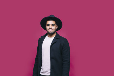 Portrait of young man standing against red background