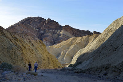 Rear view of person walking on rock against sky