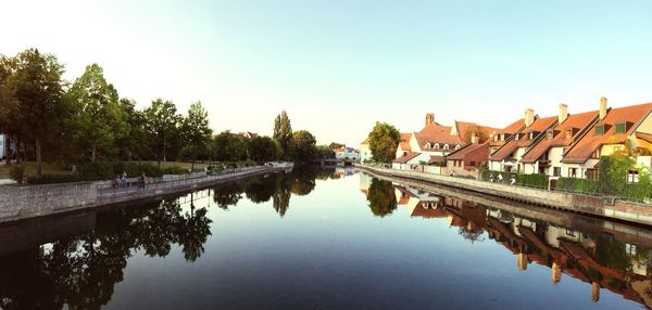 Reflection of buildings and trees in river against sky