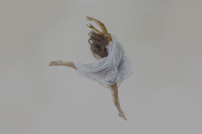 Young woman dancing against white background