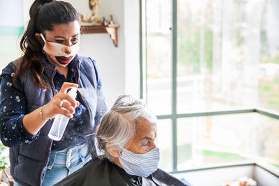 Beautician treating hair of customer at home