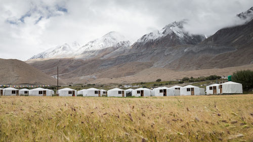 Built structure on field by mountains against sky