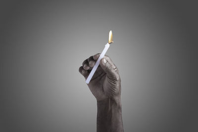 Close-up of hand holding umbrella against gray background