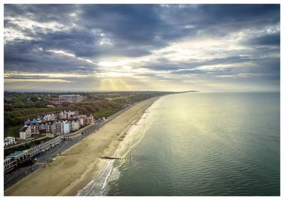 Aerial view of city by sea against sky