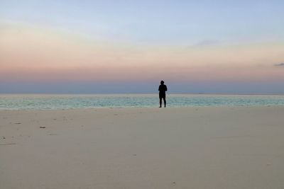 People on beach against sky during sunset