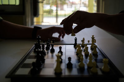 Cropped hands of people playing chess at home