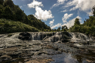 Scenic view of waterfall against sky