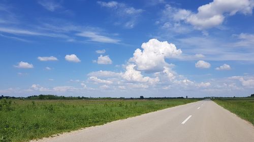 Road amidst field against sky