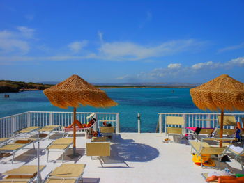 People relaxing on swimming pool at beach against blue sky